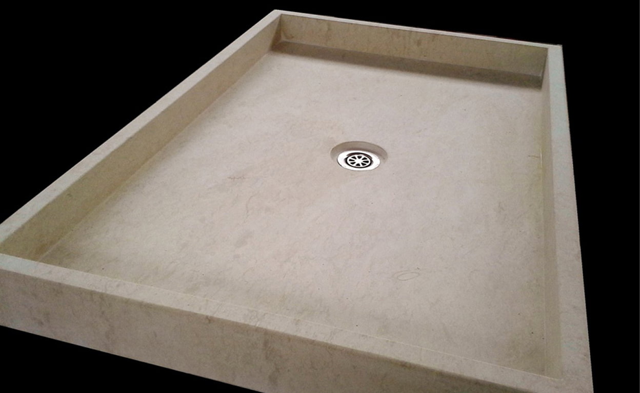 Piatto doccia in materiale composito chiaro, visto in prospettiva, con piletta centrale e bordo perimetrale, su sfondo nero, dettaglio prodotto.