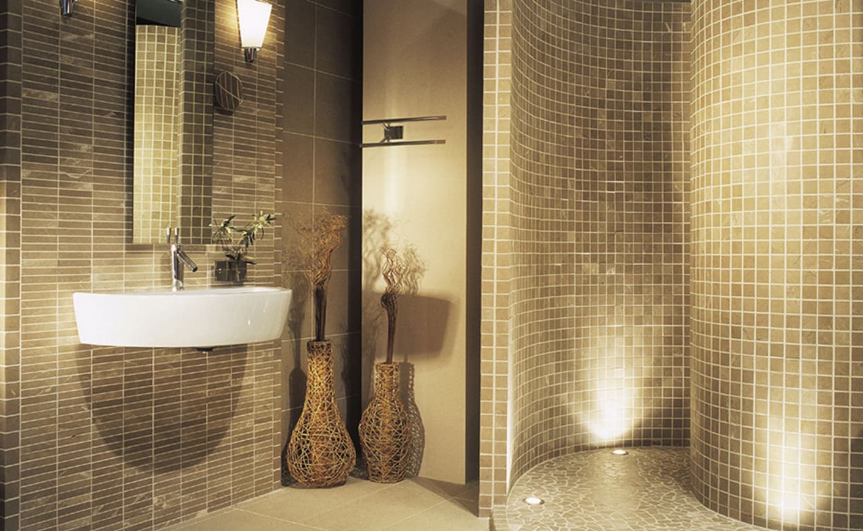 Bagno moderno con lavabo sospeso in pietra, mosaico beige e grigio a parete, nicchia illuminata e doccia walk-in con finiture eleganti, stile contemporaneo