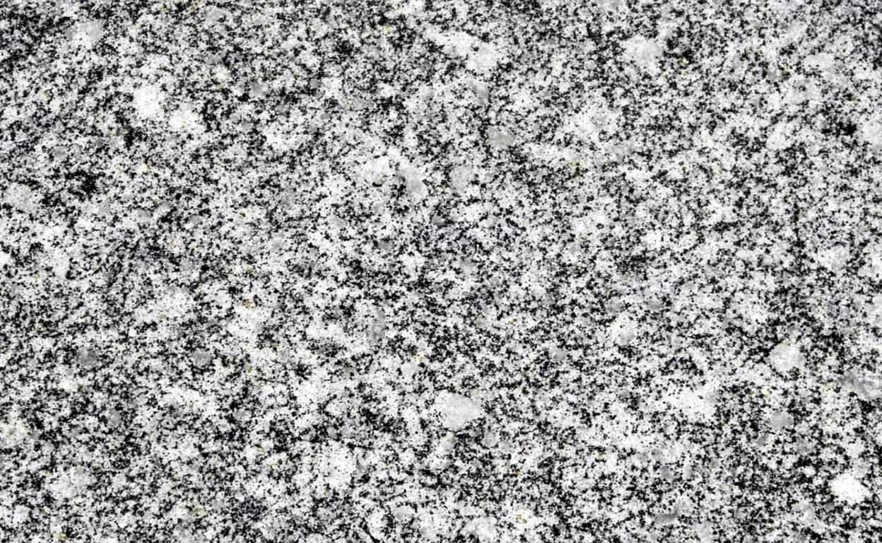 Superficie in graniglia grigia e nera con texture fine e uniforme, tipica di pietra naturale o materiale composito, sfondo ad alto contrasto