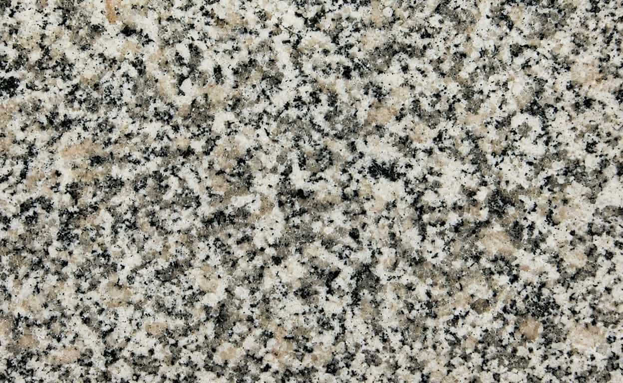 Superficie in granito grigio con venature e graniglia bianca e nera, texture naturale compatta e uniforme per rivestimenti e piani di lavoro